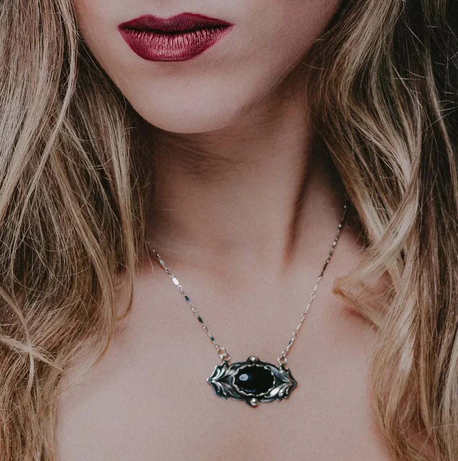 An image of a Black Onyx Sterling Silver Pendant on a woman's neck, handcrafted by Marren Jewelry in Greece.