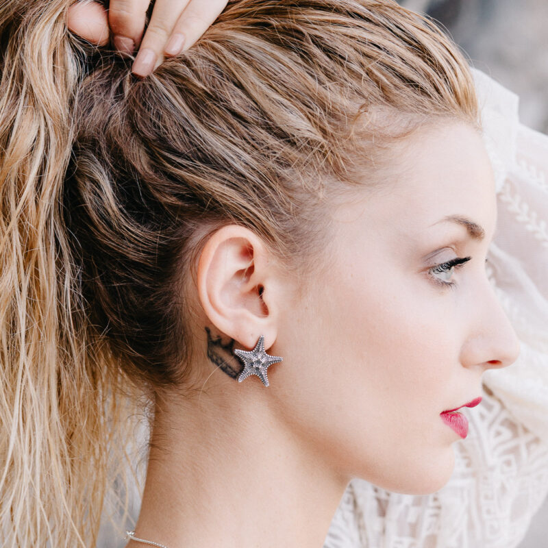 An image showing a woman wearing Starfish Sterling Silver Earrings. The earrings were handcrafted in Greece by Marren Jewelry.