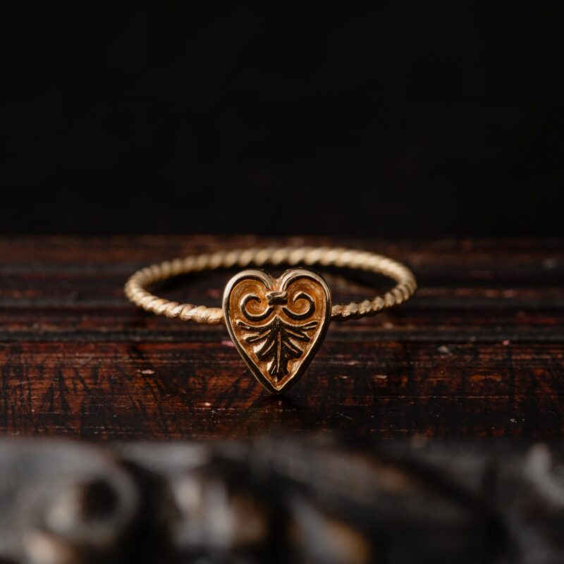 An image showing a solid gold heart acanthus ring with a twisted band