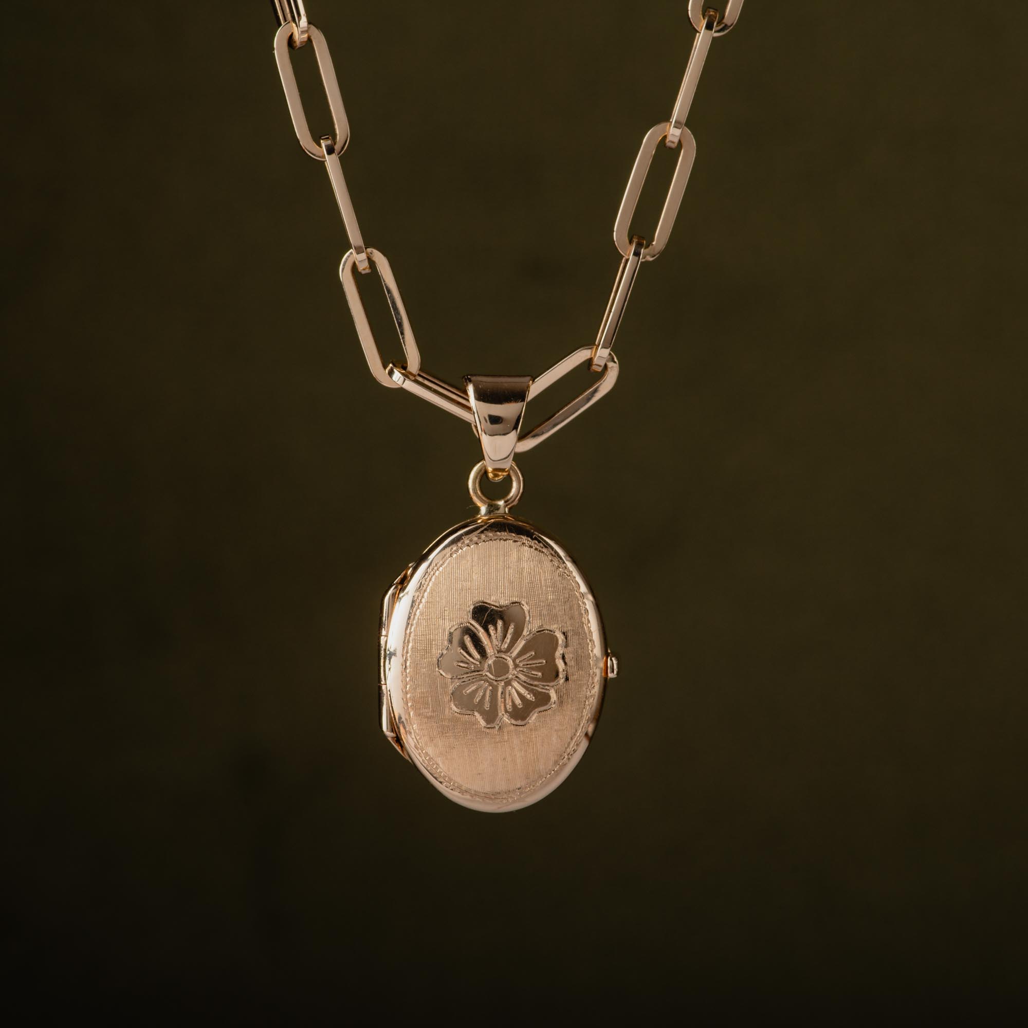 A 14K gold flower locket hanging from a gold 14K paperclip chain