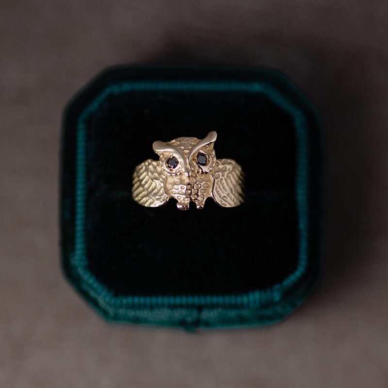 A 14K yellow gold owl ring inside a green velvet ring box