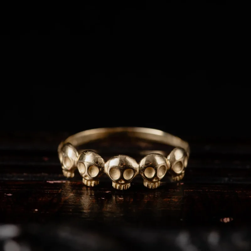 An image showing a 14K gold ring featuring 5 little skulls