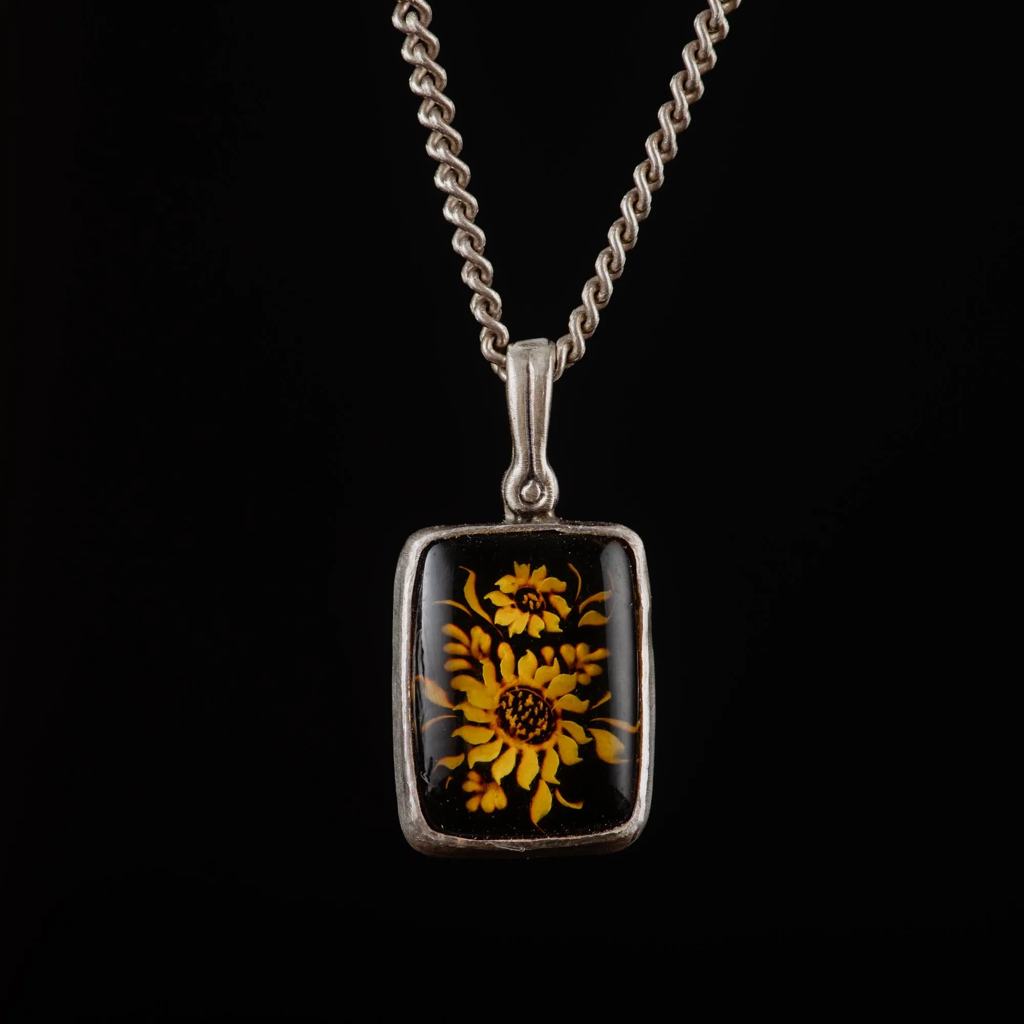 An image showing a sterling silver sunflower carved amber pendant
