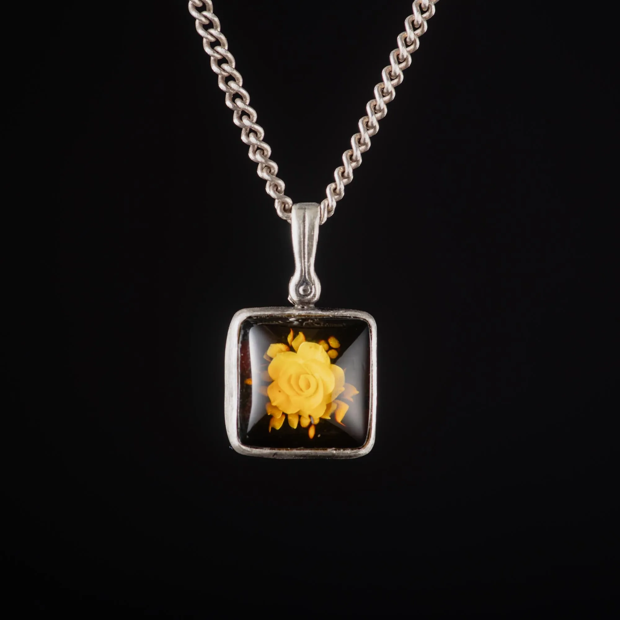 An image showing a sterling silver rose carved amber pendant