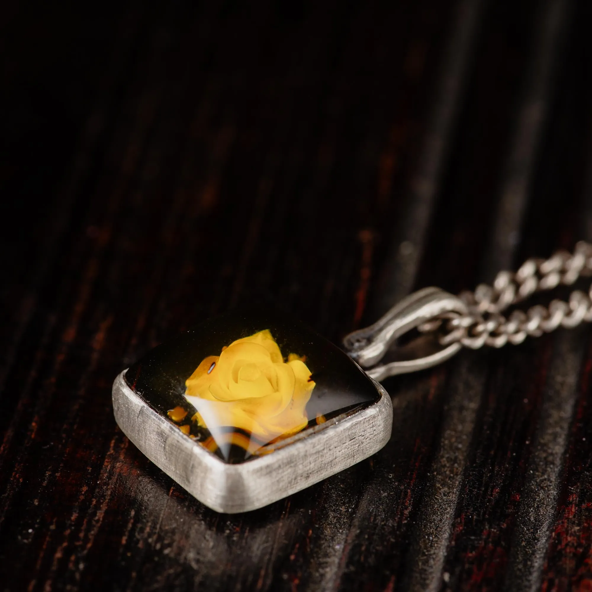 An image showing details of a sterling silver rose carved amber pendant