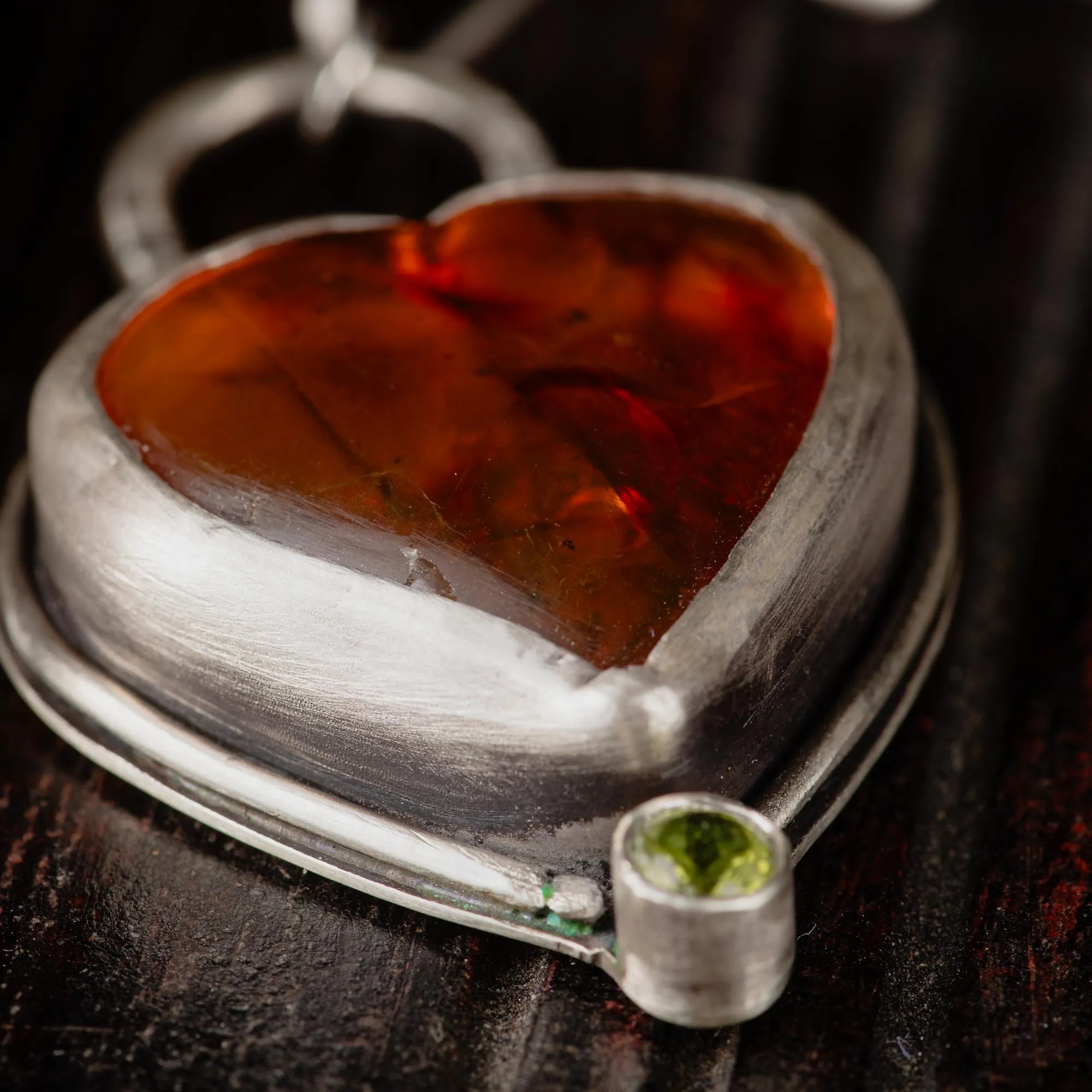 An image showing details of a glorious orange heart shaped amber sterling silver pendant with paperclip chain