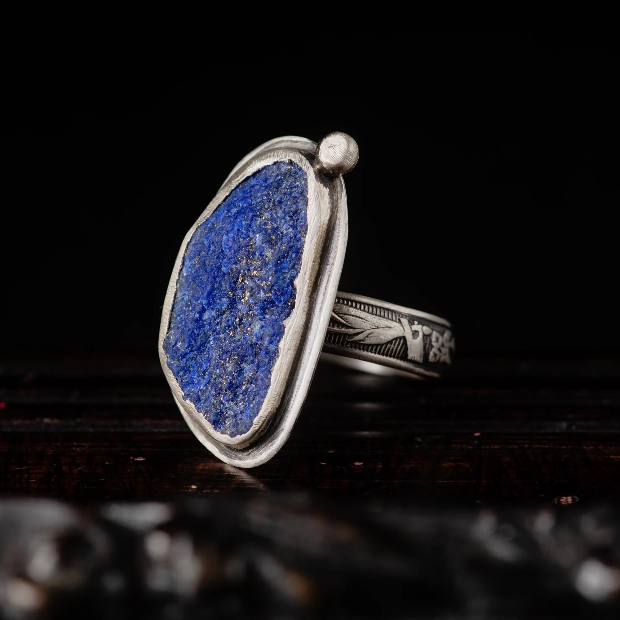 An image showing a raw blue azurite sterling silver ring with floral band from the side