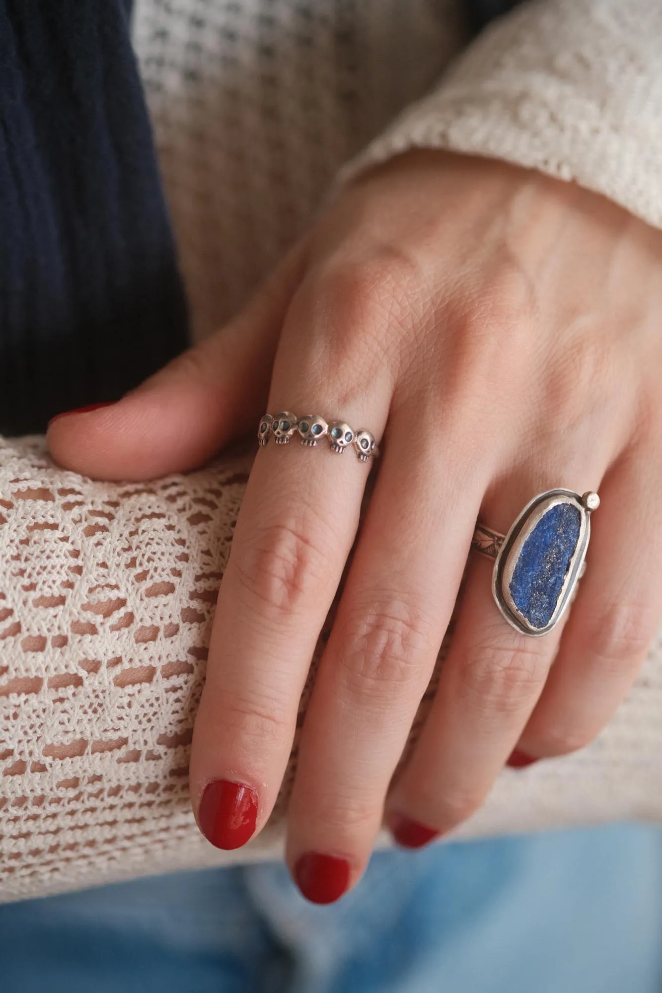 An image showing a raw blue azurite sterling silver ring and a skulls ring on a finger