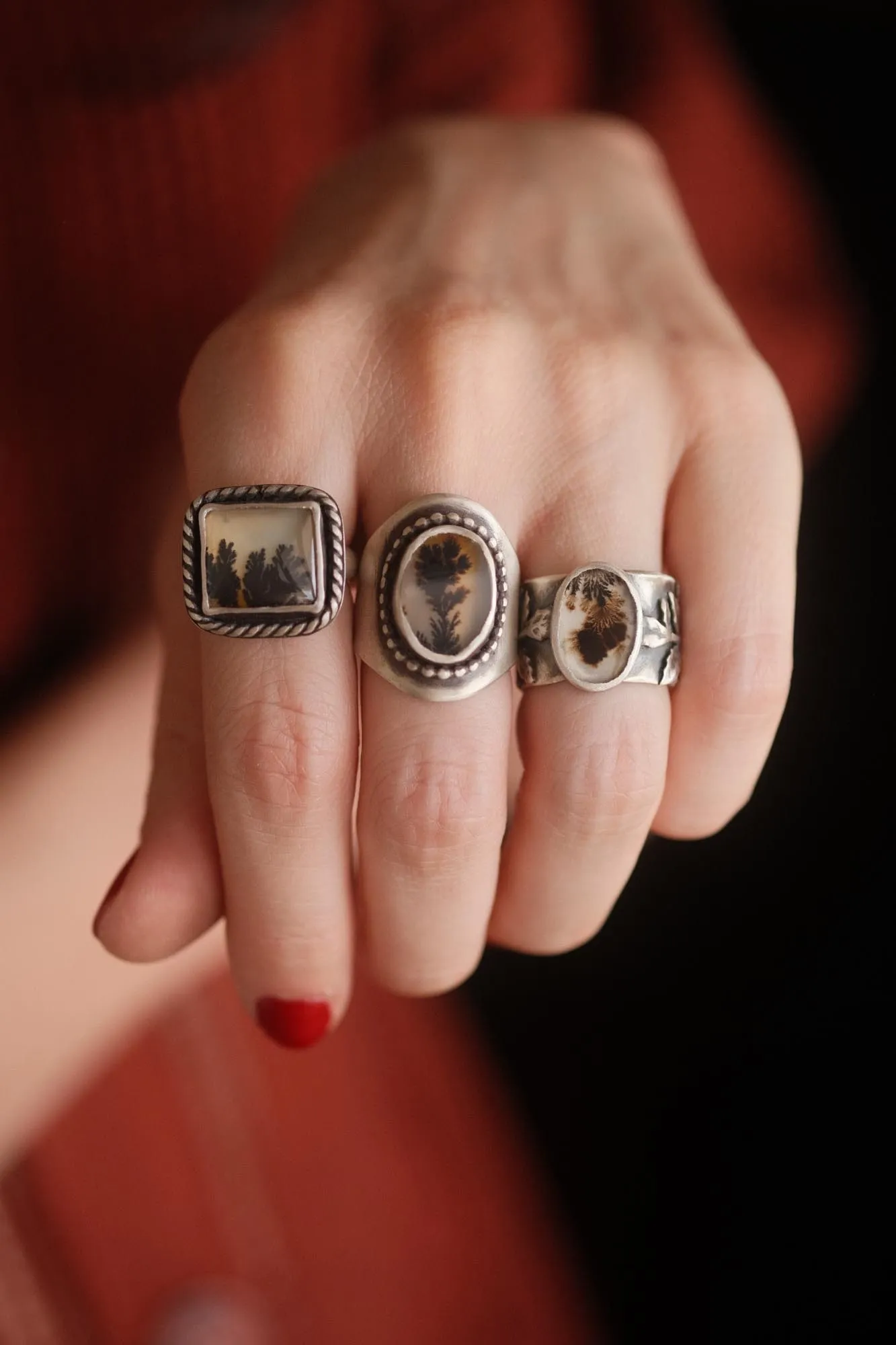 An image showing three dendritic agate rings worn on a hand