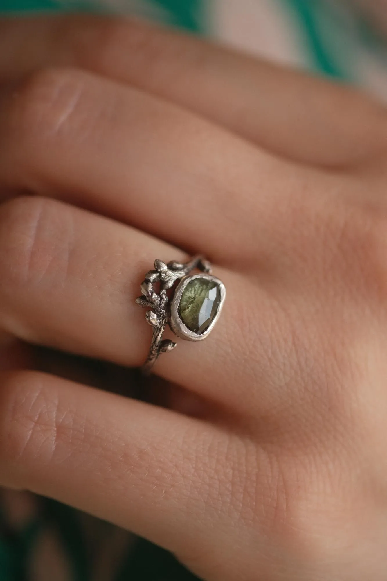An image showing a rich green tourmaline sterling silver twig ring on a finger