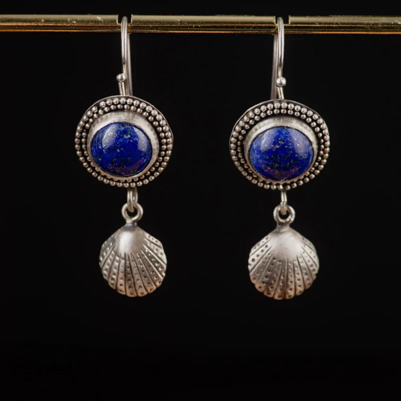 An image showing a pair of handcrafted earrings, featuring lapis gemstones ans silver shells