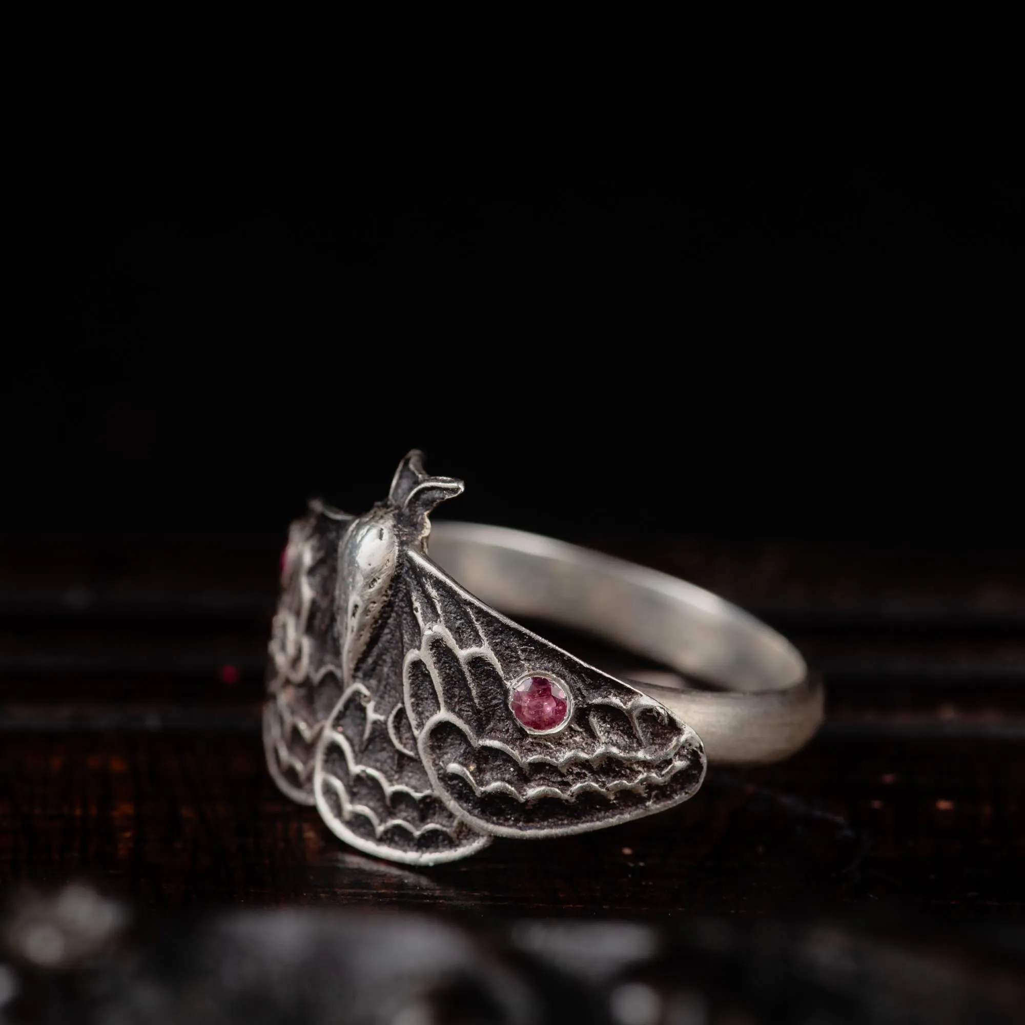 An image showing a sterling silver moth ring with two pink tourmalines from the side