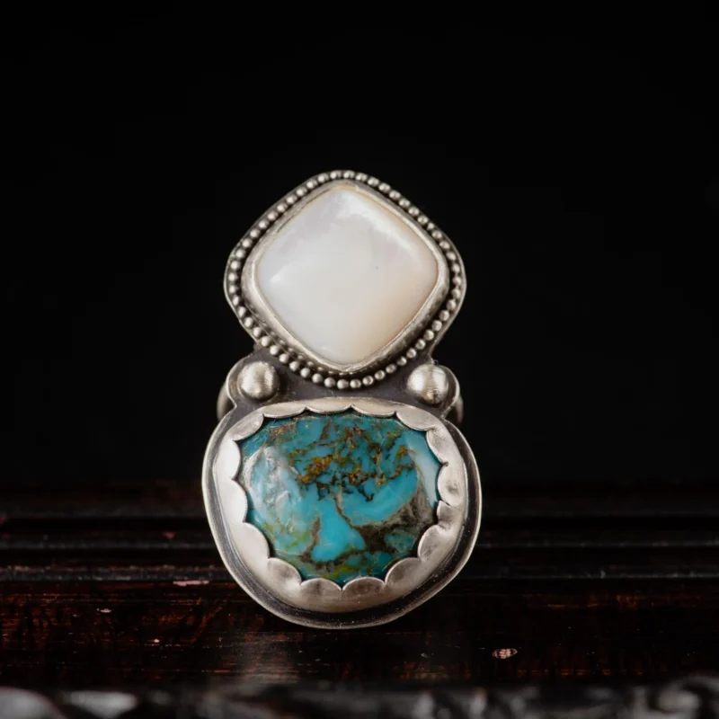 An image showing a wide ring with a combination of turquoise and mother of pearl gemstones