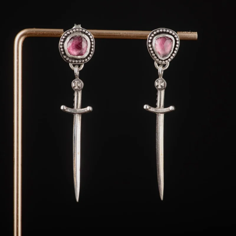 An image showing a pair of dagger sterling silver earrings featuring pink tourmalines