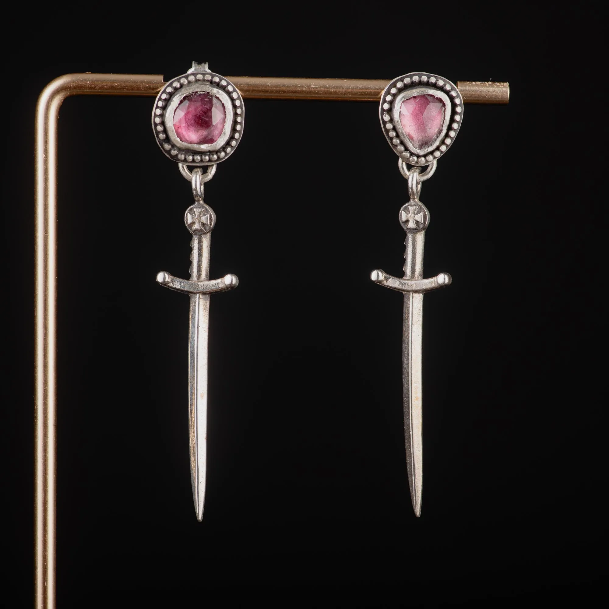 An image showing a pair of dagger sterling silver earrings featuring pink tourmalines