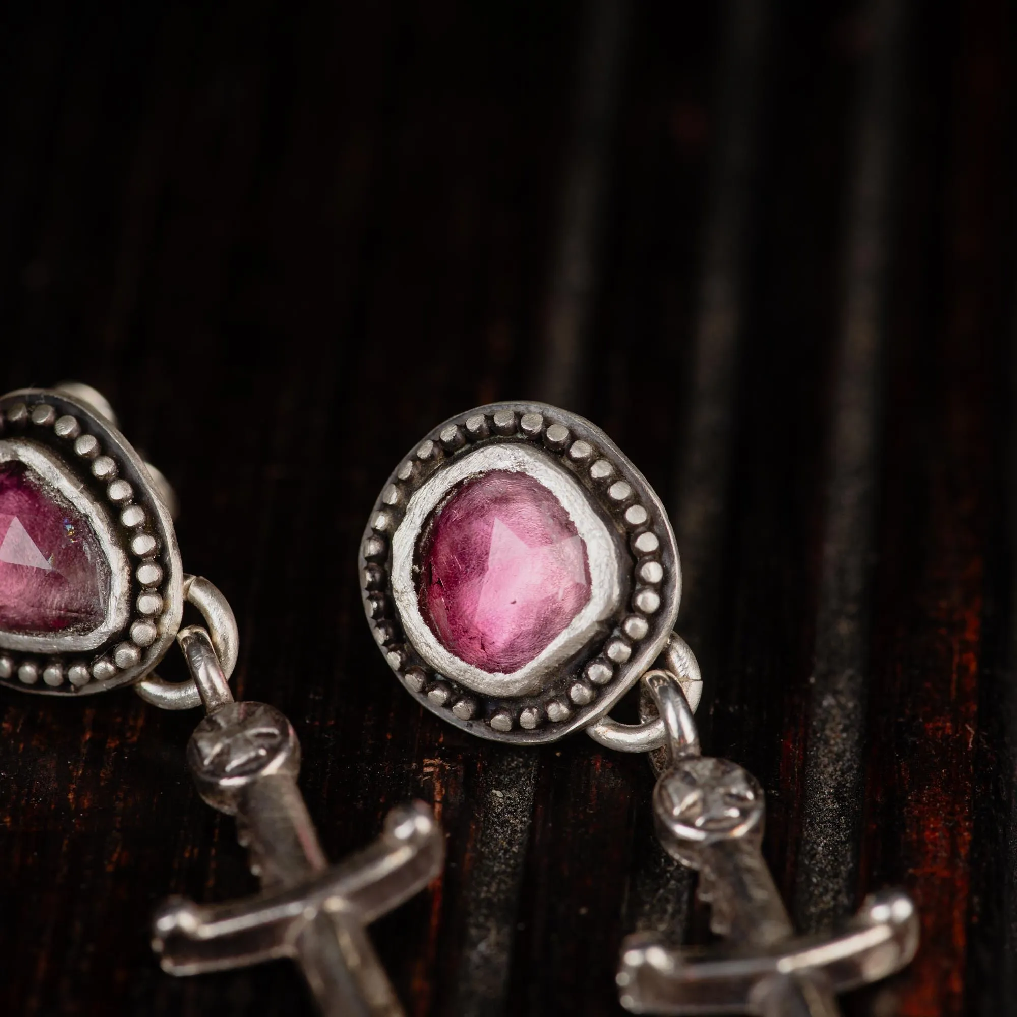 An image showing details of a pair of dagger sterling silver earrings featuring pink tourmalines