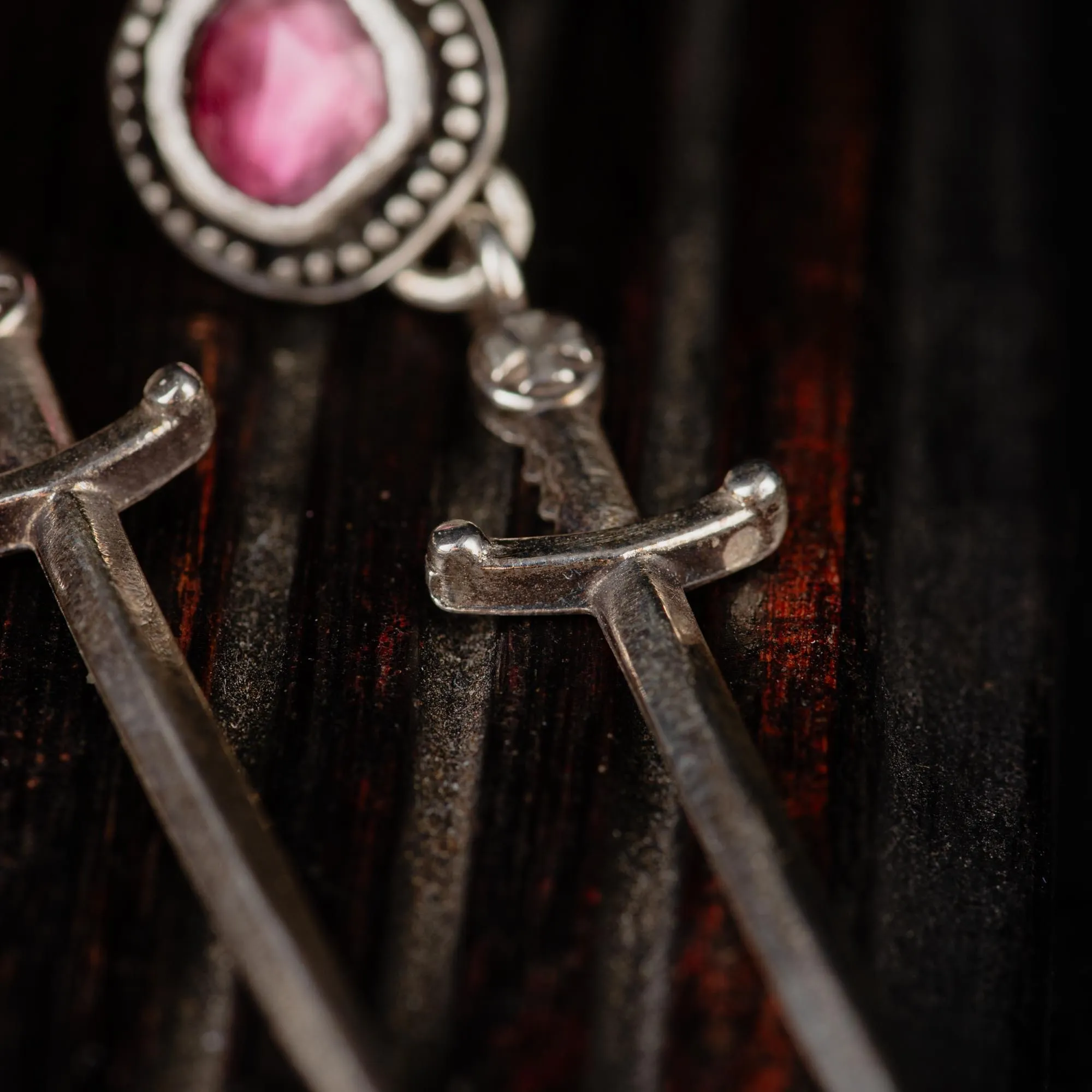 An image showing details of a pair of dagger sterling silver earrings featuring pink tourmalines