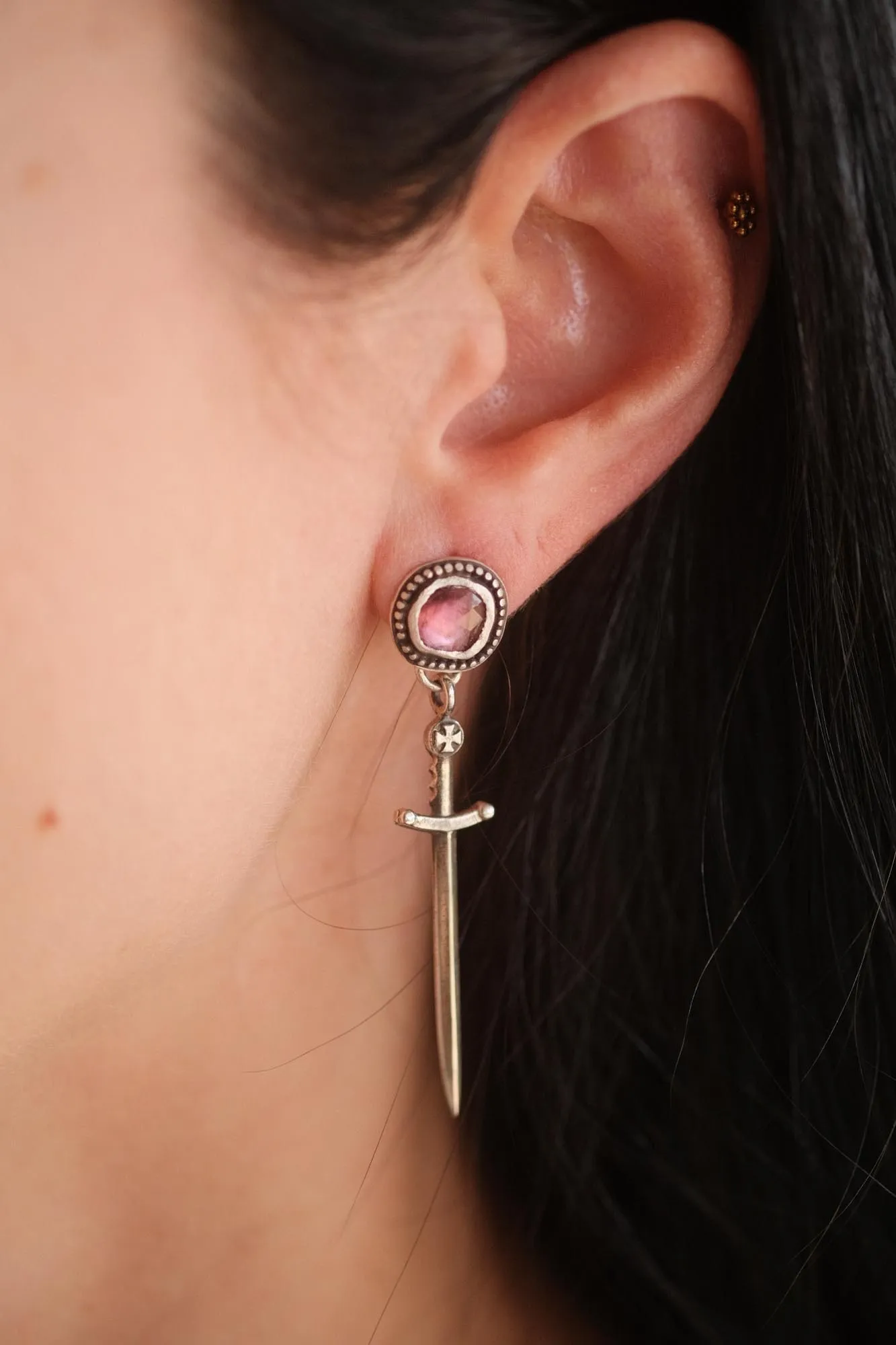 An image a dagger sterling silver earring featuring pink tourmaline on an ear