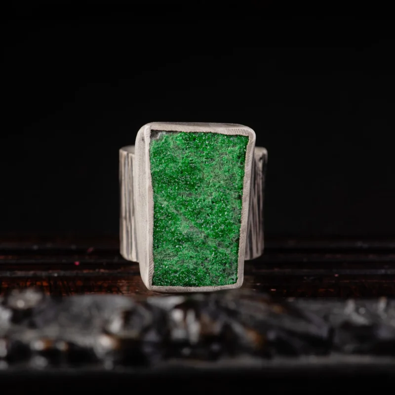 An image of a sterling silver hammered wide band ring featuring a raw druzy rich green uvarovite. OOAK Ring
