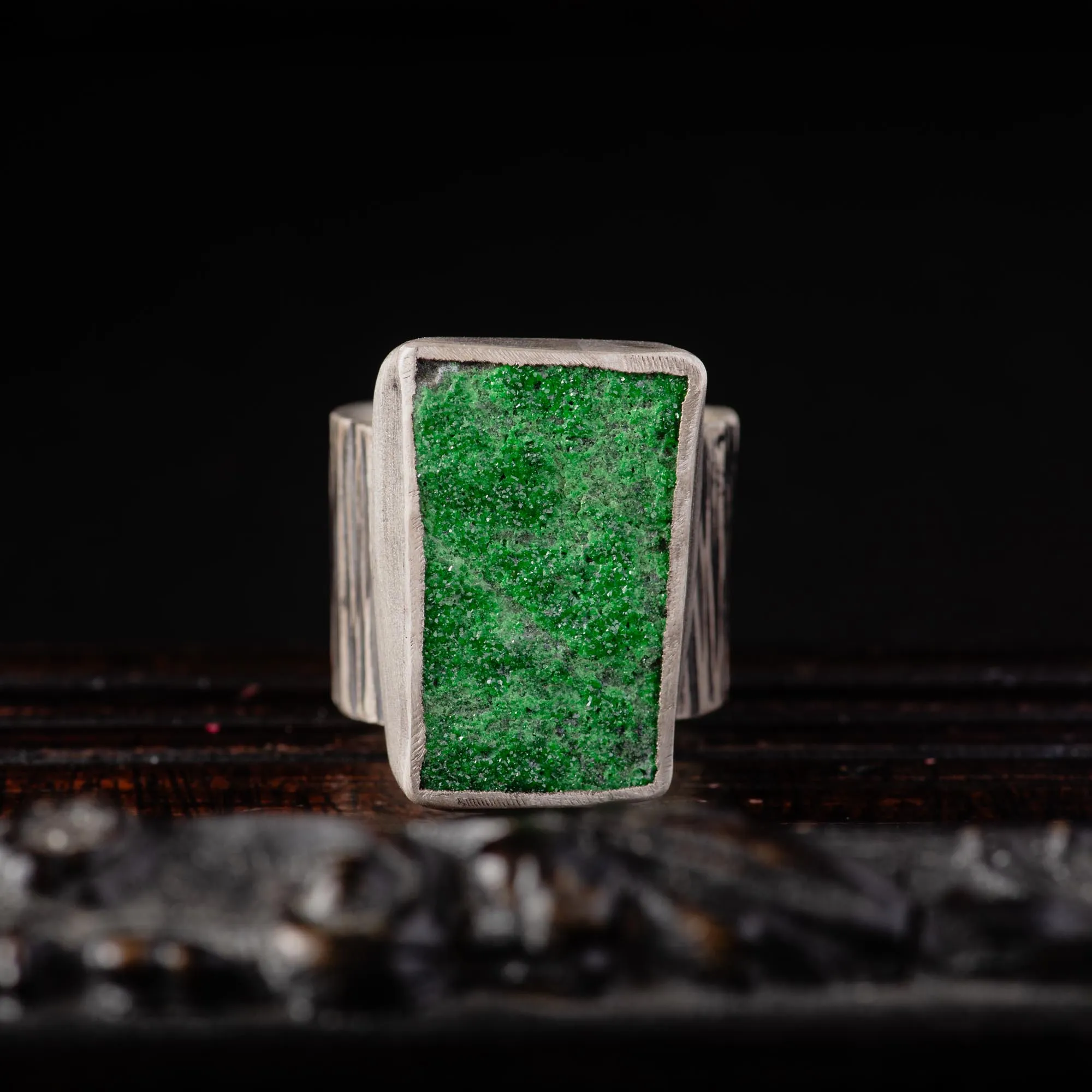 An image of a sterling silver hammered wide band ring featuring a raw druzy rich green uvarovite. OOAK Ring