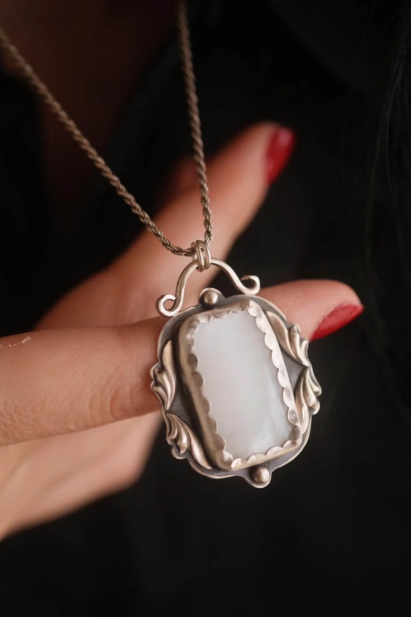An image showing details of a white selenite sterling silver pendant that is victorian inspired