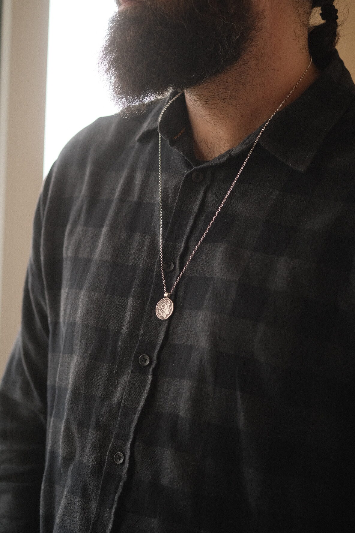 an image showing a man in plaid shirt wearing a sterling silver pendant featuring alexander the great