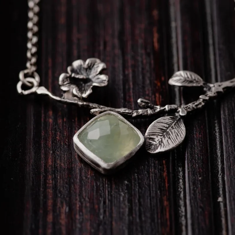 An image showing a delicate sterling silver twig with a prehnite gemstone in details