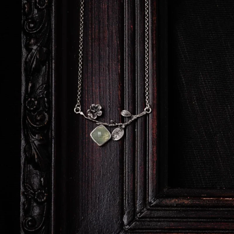 An image showing a delicate sterling silver twig with a prehnite gemstone