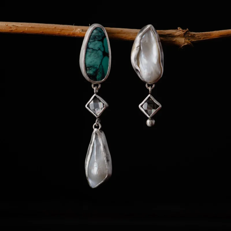 An image showing sterling silver earrings with natural turquoise, mother of pearl and baroque pearls on a tree branch
