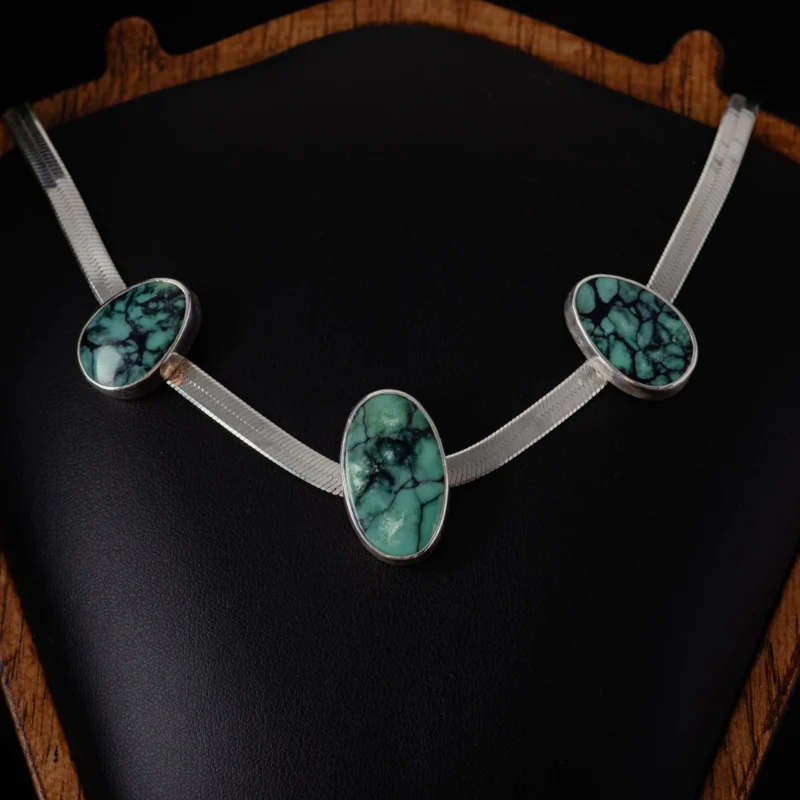 An image showing sterling silver herringbone necklace featuring three natural turquoise