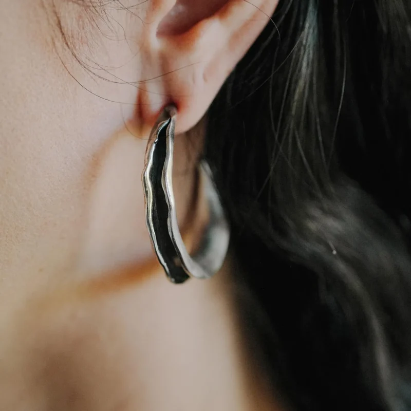 An image showing hand formed scultpural earrings on an ear