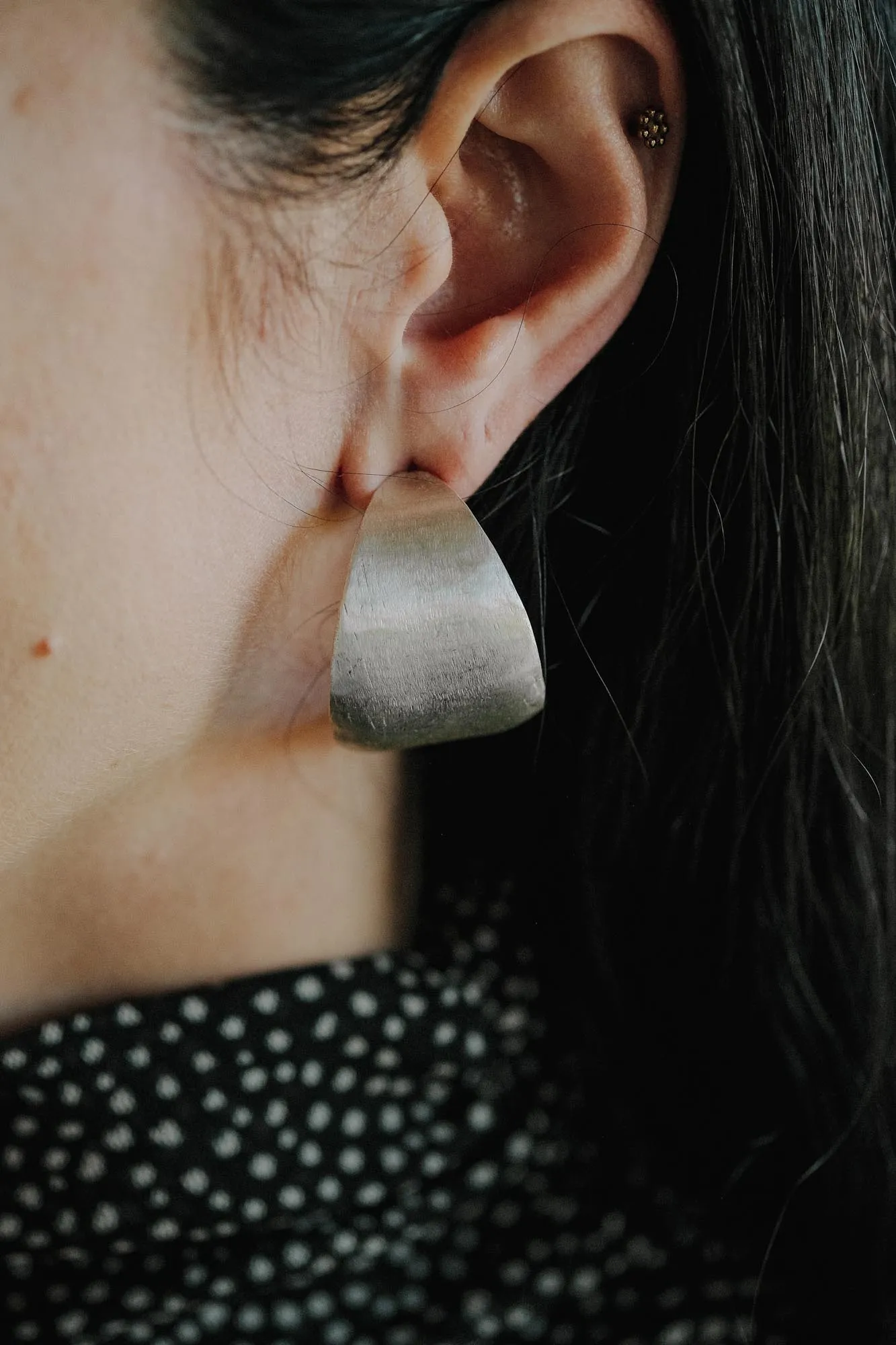 An image showing chunky sterling silver hoops on an ear